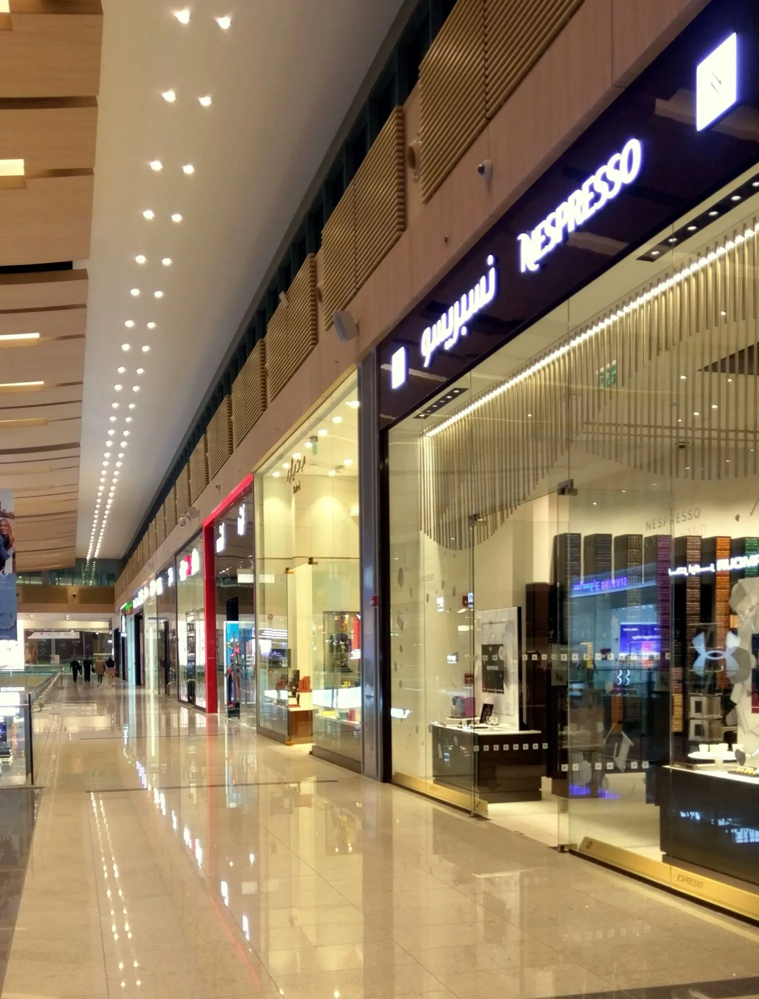 Polished retail concourse with glazed shopfronts and suspended ceilings inside a Doha mall